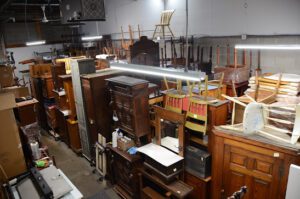 Warehouse stacked with assorted vintage wooden furniture