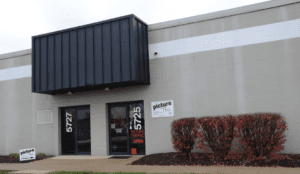 Commercial storefront with black awning and shrubs
