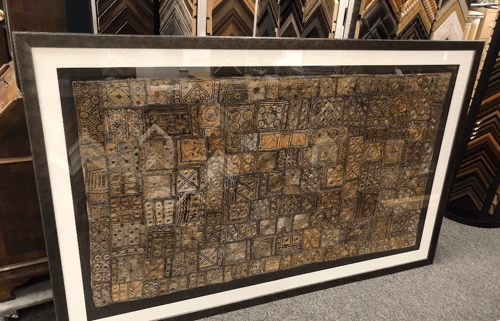 Framed abstract mosaic artwork leaning on floor