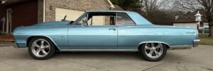 Classic light blue two-door car on driveway